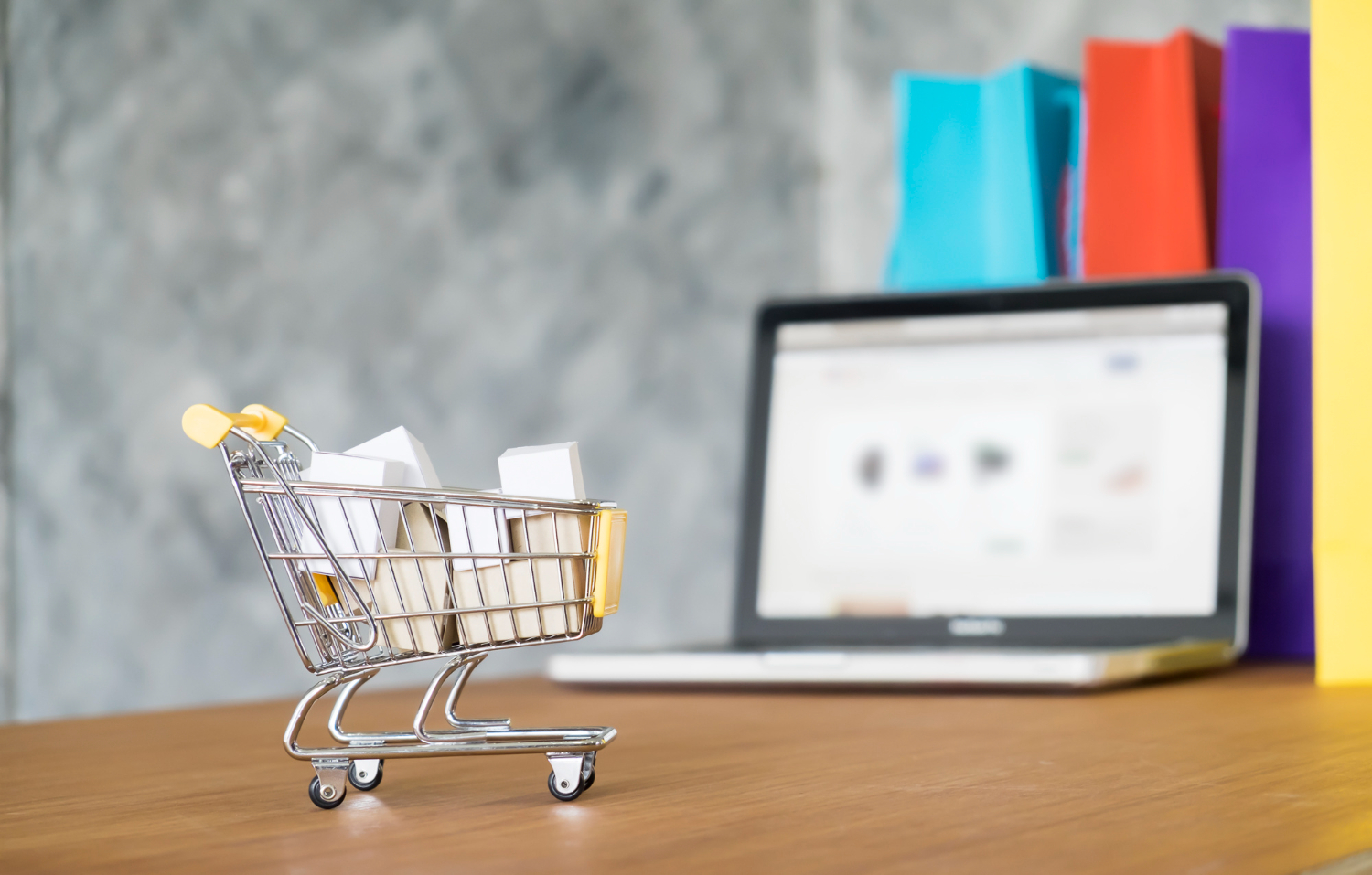 E-commerce shopping cart on laptop screen with shopping bags